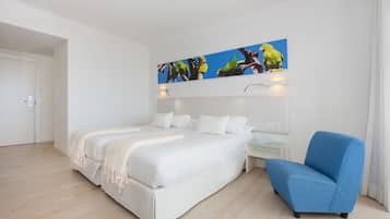 Een moderne hotelkamer met een groot bed, een blauwe fauteuil en een schilderij van papegaaien aan de muur.