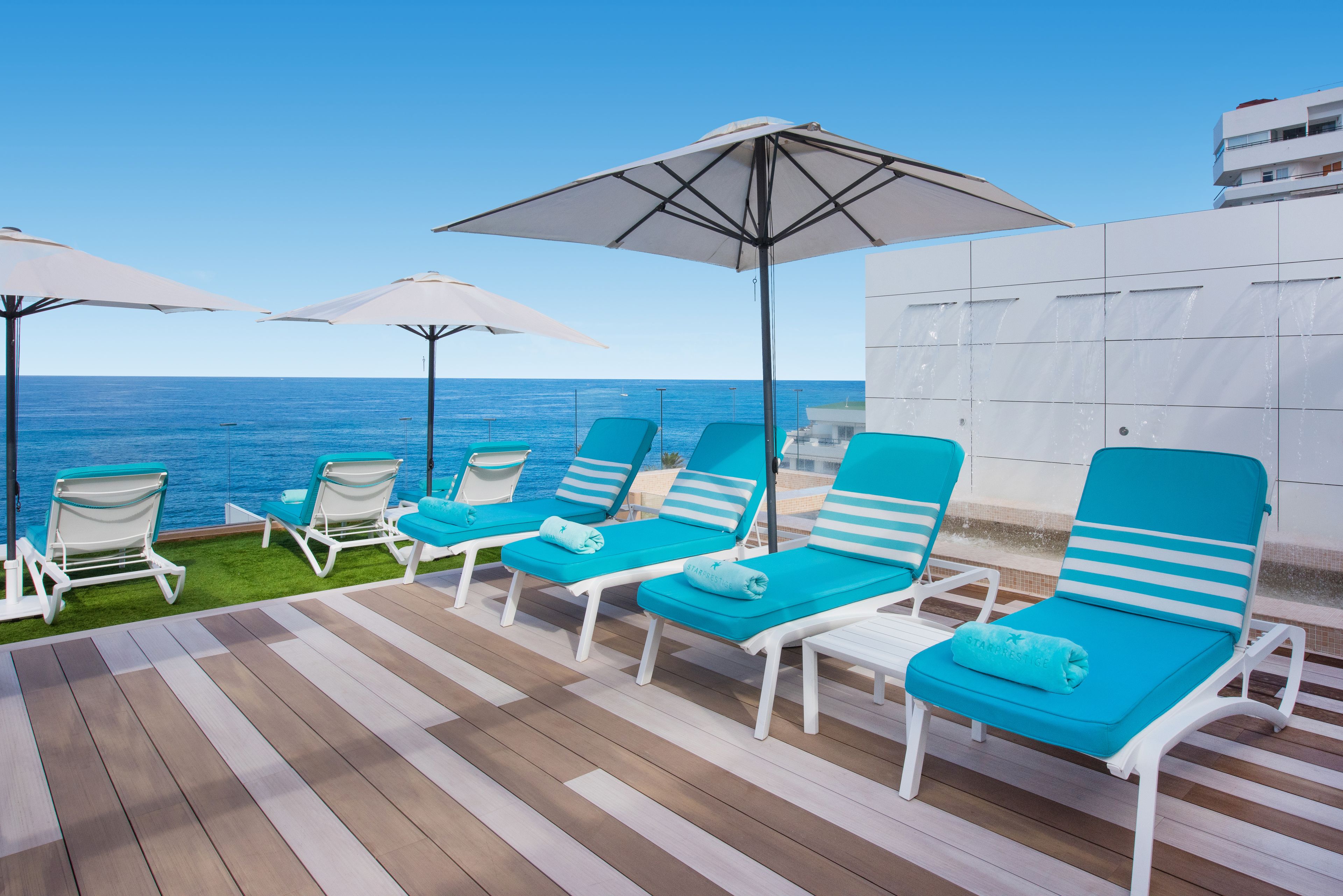 A deck with lounge chairs and umbrellas overlooking the sea.