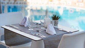Mesa para dos personas con vistas a una piscina.