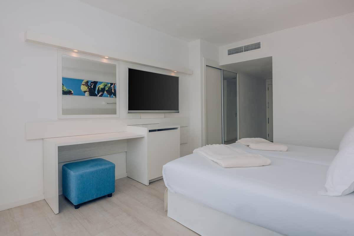 Quarto de hotel moderno com cama, escrivaninha, televisão de tela plana, espelho e closet espaçoso.