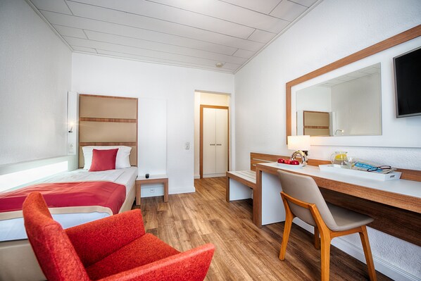 Una habitación de hotel con cama, escritorio, silla, espejo y puerta.