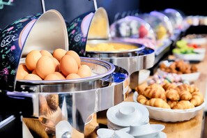 Un buffet proposant une variété de plats, notamment des œufs, du fromage et des viennoiseries.