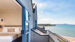 Un balcón con vista al mar y una cama con sábanas blancas.