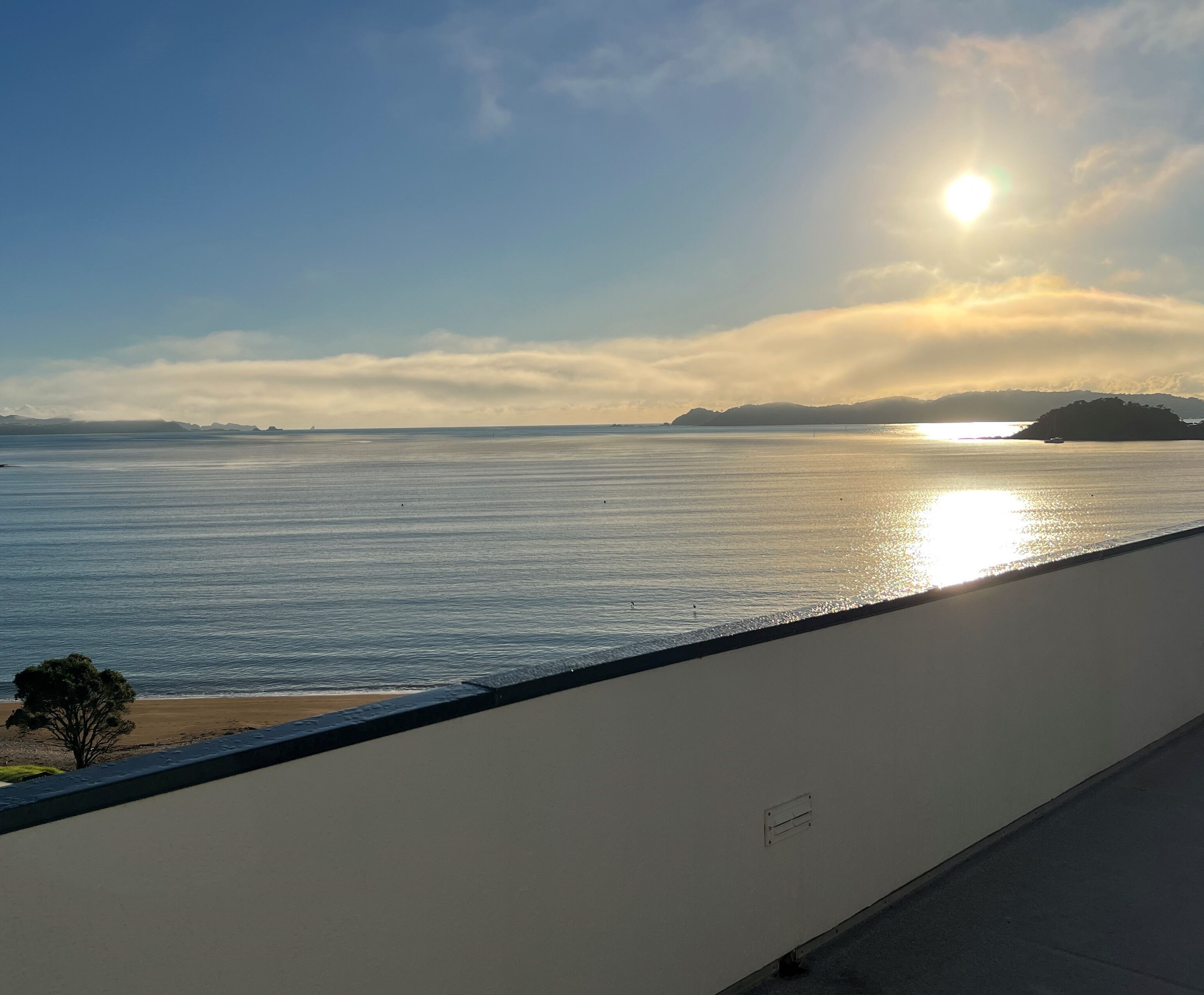 A coastal view with a clear sky, calm sea, and distant landforms.