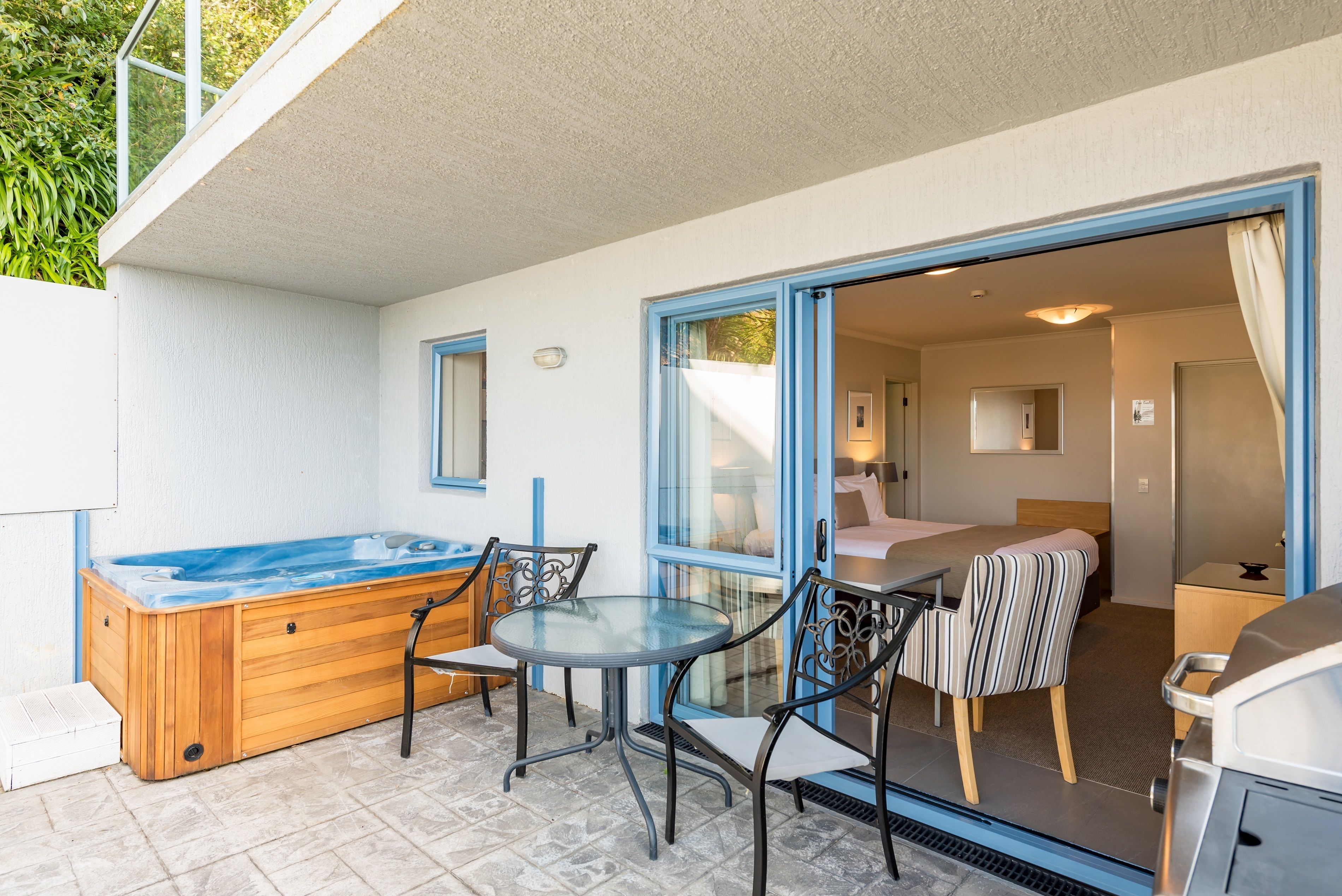 A cozy outdoor patio with a hot tub, a glass table, and chairs.