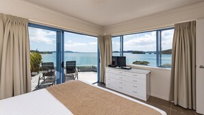 Un dormitorio con una cama grande, un aparador, un televisor y vistas al mar.