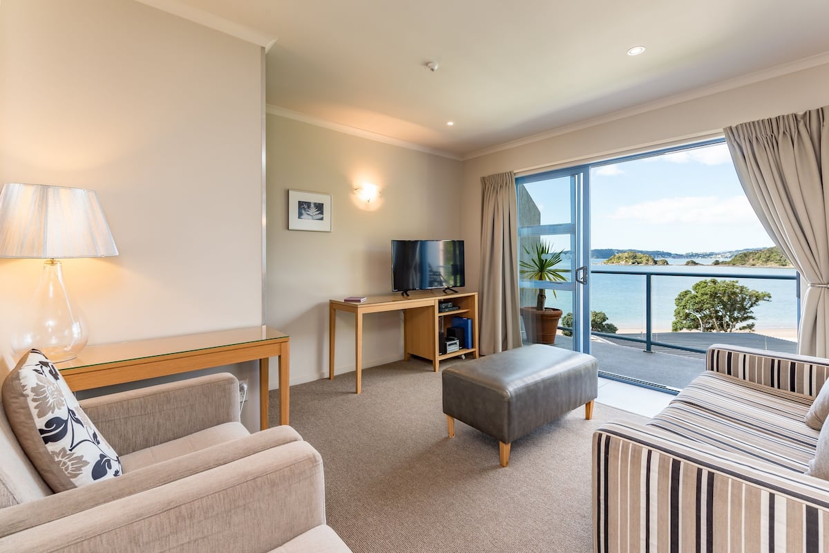 Ett hotellrum med ett stort fönster, en TV, ett skrivbord och en soffa.