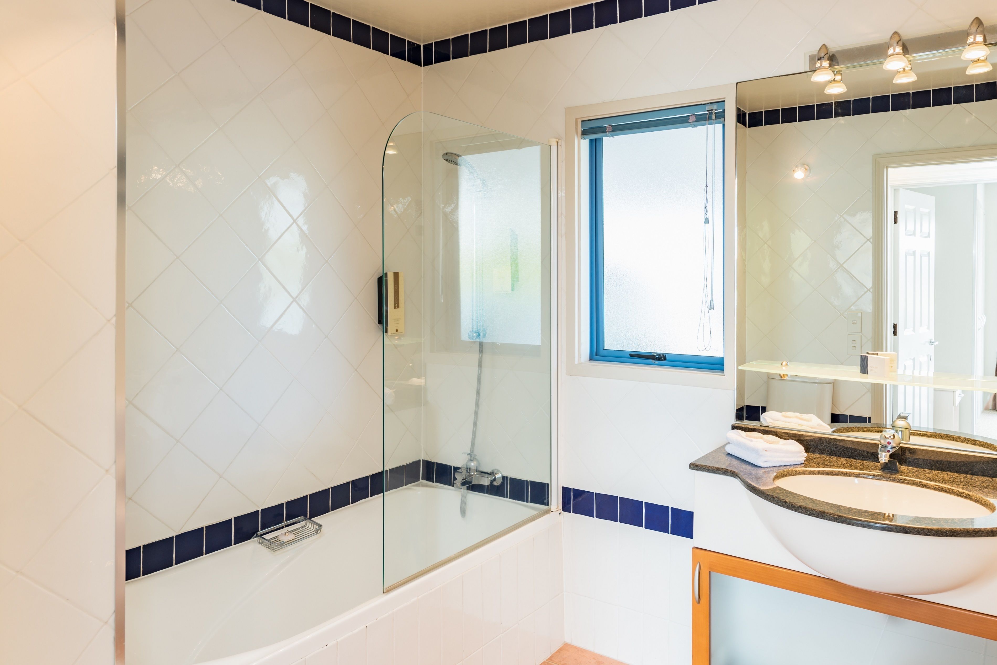 A modern bathroom with a glass-enclosed shower, a sink with a vanity, and a window providing natural light.