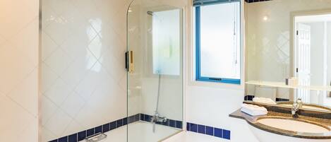 A modern bathroom with a glass-enclosed shower, a sink with a vanity, and a window providing natural light.