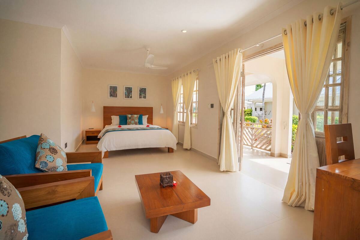 A bedroom with a bed, a sofa, a coffee table, and a view of the outside.