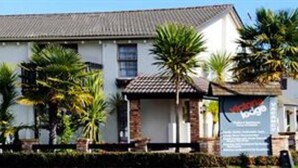 A two-story building with a flat roof, multiple windows, and a signboard on the right side. - Victoria Lodge (Rotorua)
