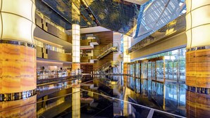 A modern hotel lobby with a reflective floor, a central staircase, and a glass elevator. - The Westin Beijing Chaoyang (Beijing)