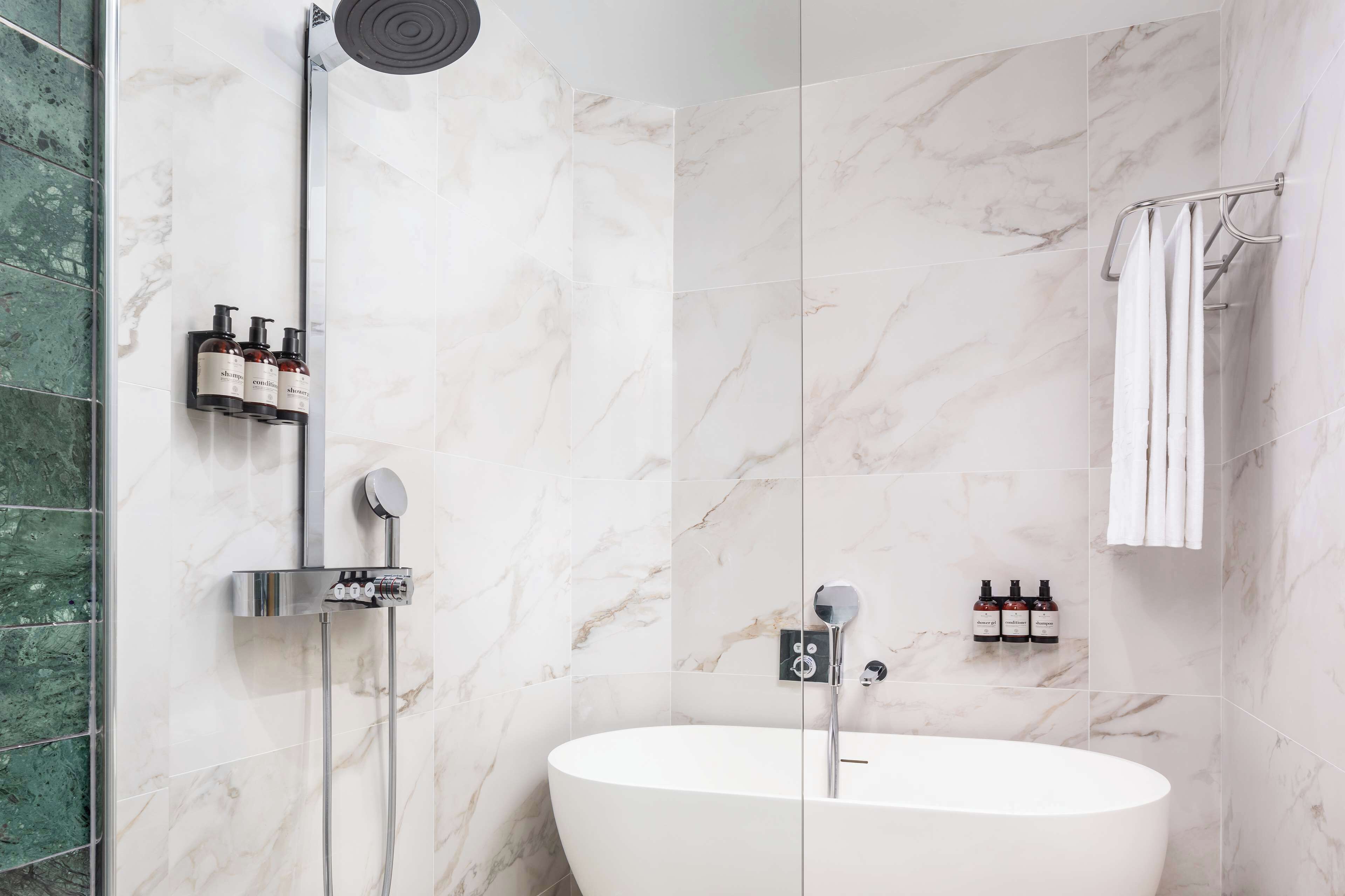 Une salle de bain moderne avec une baignoire sur pieds, une douche à parois de verre et un porte-serviettes.