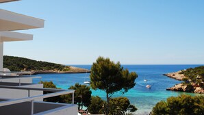 A coastal view with a clear sky, a tree in the foreground, and boats on the water. - Sandos El Greco Hotel - Adults Only (Sant Joan de Labritja)