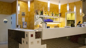 A bar area with a counter, shelves of bottles, and hanging lights. - Smy Bologna Centrale (Bologna)