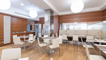 Een modern restaurant met verschillende eetgedeeltes, een minibar en een grote spiegel.