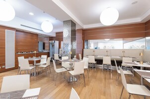 Een modern restaurant met verschillende eetgedeeltes, een minibar en een grote spiegel.