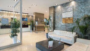 A modern lobby with a reception desk, seating area, and decorative wall panels. - Smy Bologna Centrale (Bologna)