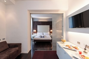 Une chambre d’hôtel moderne équipée d’un lit, de tables de chevet, d’une télévision et d’un plateau de petit-déjeuner.