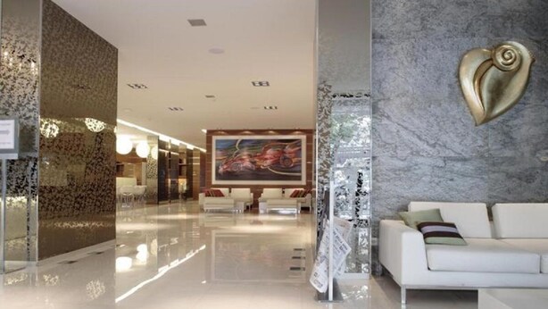 A modern hotel lobby with a marble reception desk, a white sofa, and a large abstract painting on the wall. - Smy Bologna Centrale (Bologna)