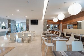 Un hall d’hôtel moderne comprenant un comptoir d’accueil, un espace salon et un coin repas.