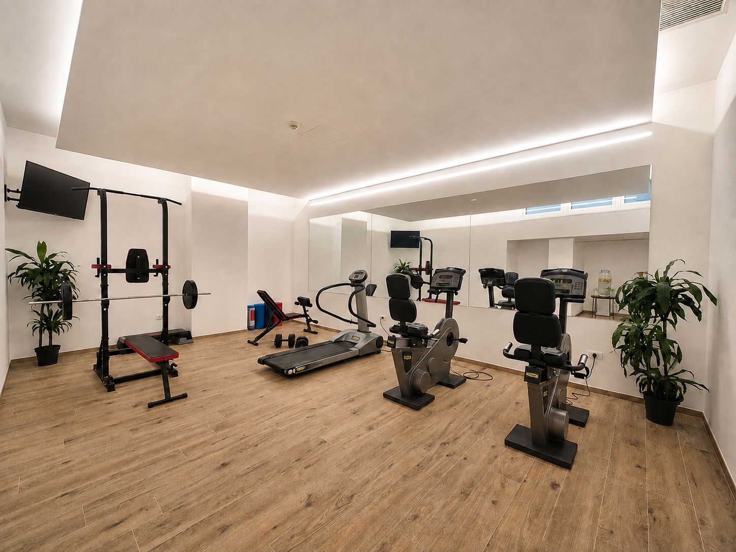 Een moderne sportschool met diverse fitnessapparaten, waaronder een loopband, een gewichtbank en hometrainers.