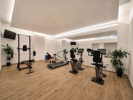 Un gimnasio moderno con diversos equipos de ejercicio, como cintas de correr, bancos de pesas y bicicletas estáticas.