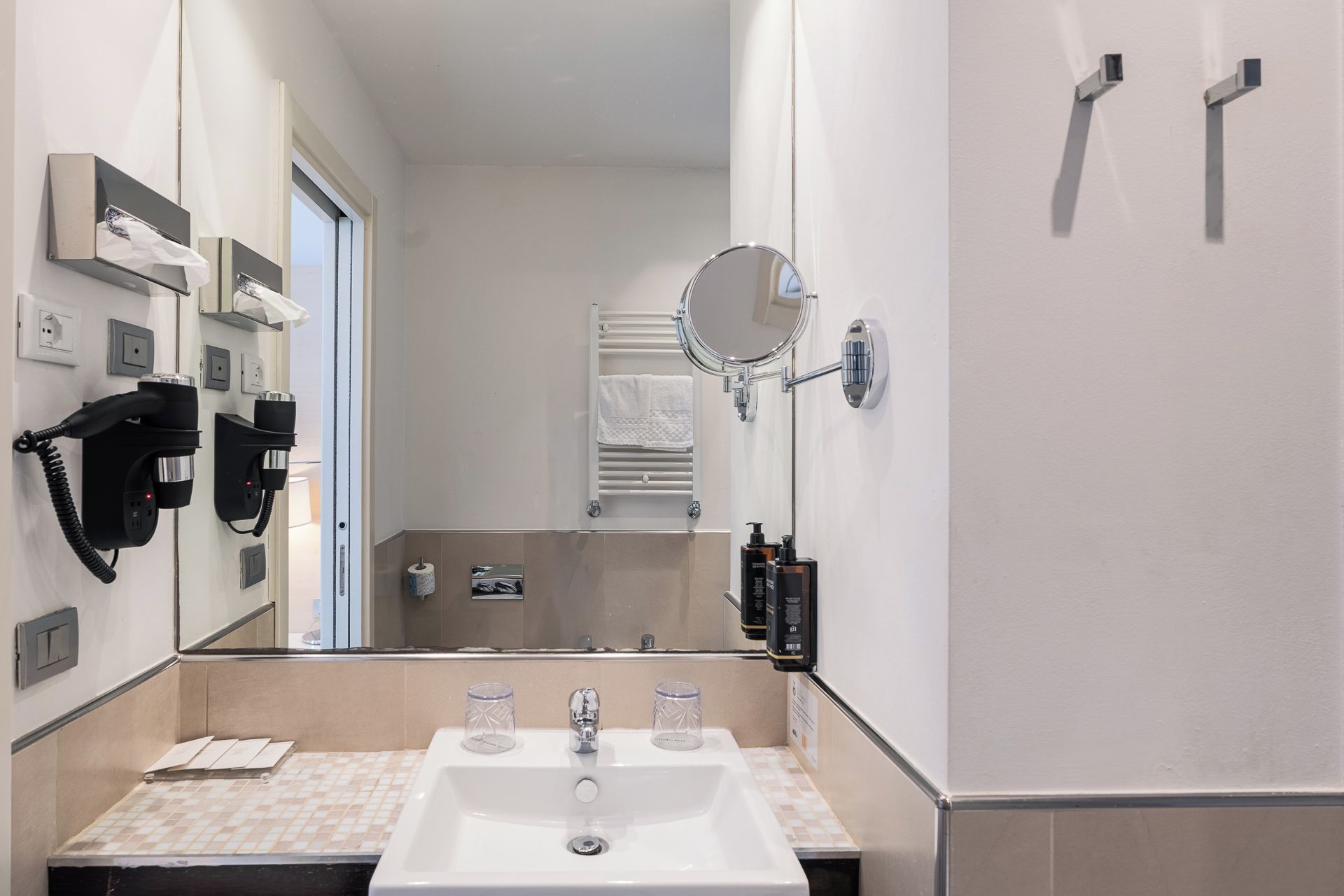 Un bagno con lavandino, specchio, portasciuga e telefono.