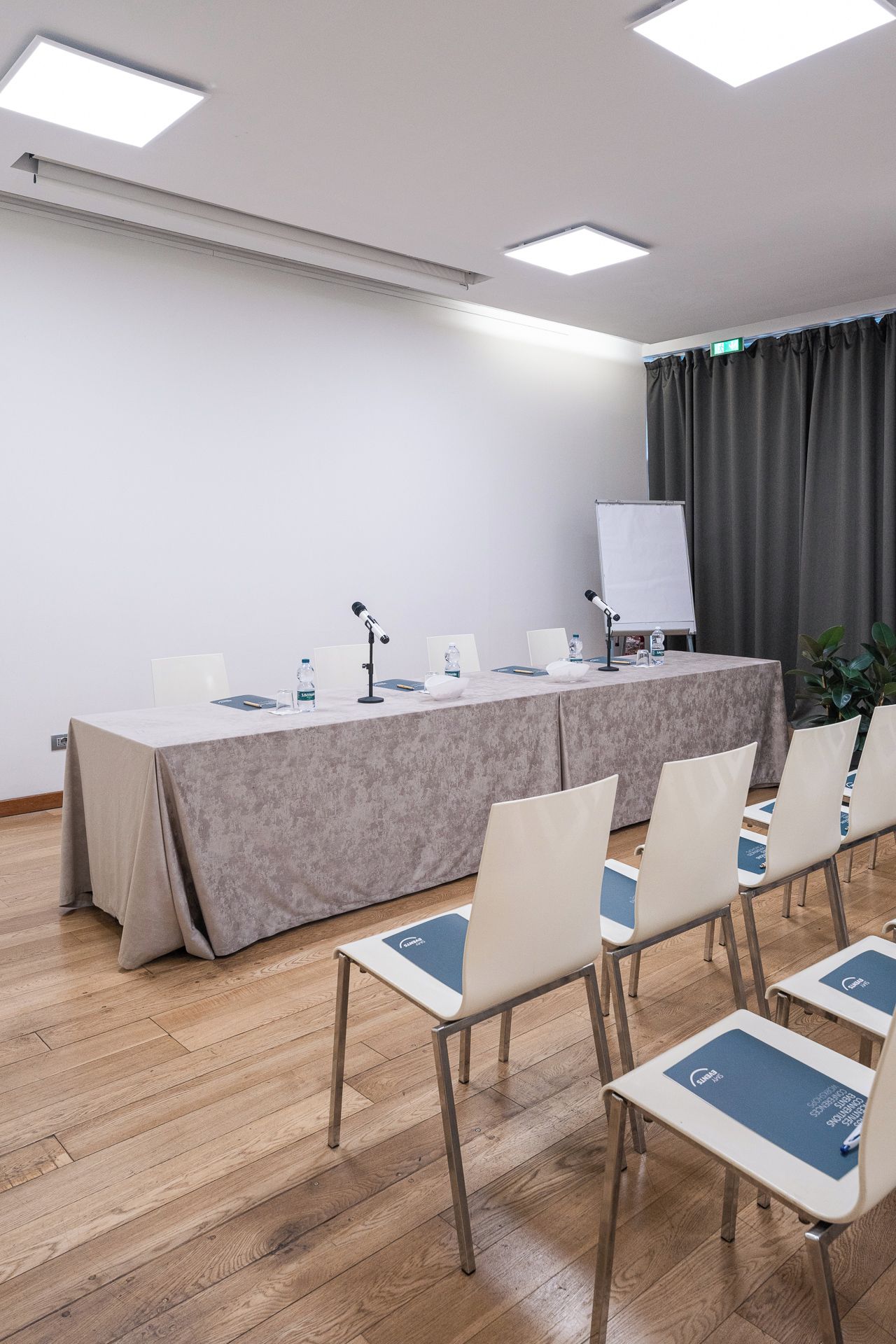 Una sala conferenze con un lungo tavolo, sedie, una lavagna e uno schermo per proiettore.