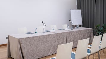 Una sala conferenze con un lungo tavolo, sedie, una lavagna e uno schermo per proiettore.