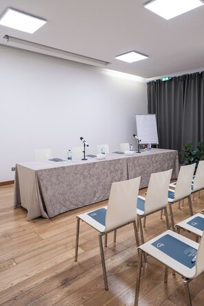 Ett konferensrum med ett långt bord, stolar, en whiteboard och en projektorduk.