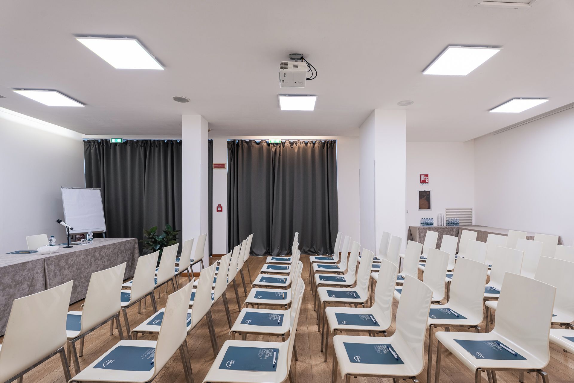 A conference room with rows of chairs, a projector, and a whiteboard.