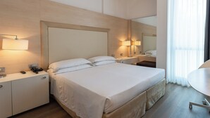 A hotel room with a large bed, bedside tables, a desk, and a mirror. - Smy Bologna Centrale (Bologna)