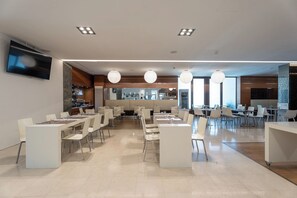 A modern restaurant with multiple dining tables and chairs, a bar area, and a television mounted on the wall. - Smy Bologna Centrale (Bologna)