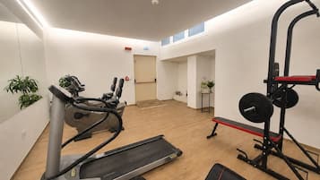 Een sportschool met cardioapparatuur, losse gewichten en een spiegel.