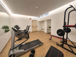 Een sportschool met cardioapparatuur, losse gewichten en een spiegel.