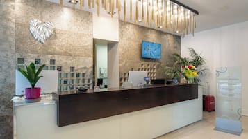 A reception desk with a modern design, a digital screen, and a decorative wall with a heart-shaped art piece.
