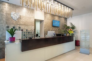 Un comptoir d’accueil au design moderne, un écran numérique et un mur décoratif orné d’une œuvre d’art en forme de cœur.
