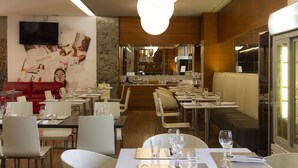 A restaurant with a modern interior, featuring a red sofa, white dining tables, and a large mirror. - Smy Bologna Centrale (Bologna)