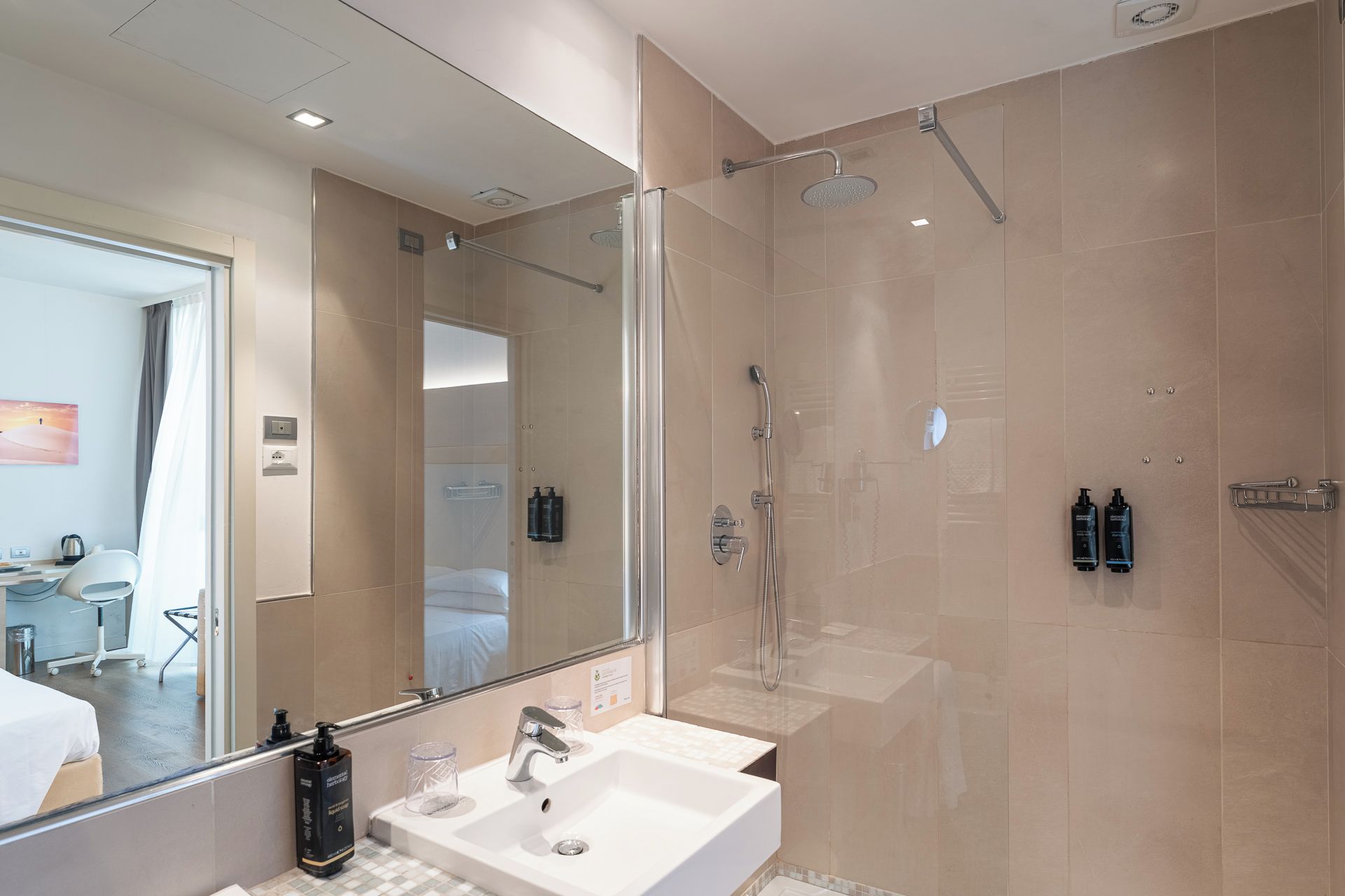 A modern bathroom with a glass-enclosed shower, a white sink, and a large mirror.