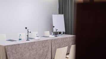 Ein Konferenzraum mit einem langen Tisch, zwei Mikrofonen, einer Whiteboard und Stühlen.
