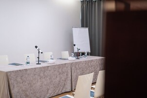A conference room with a long table, two microphones, a whiteboard, and chairs.