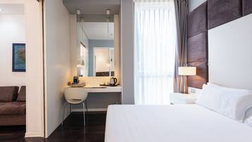 Een hotelkamer met een bed, een bureau met stoel, een koffiezetapparaat en een lamp.