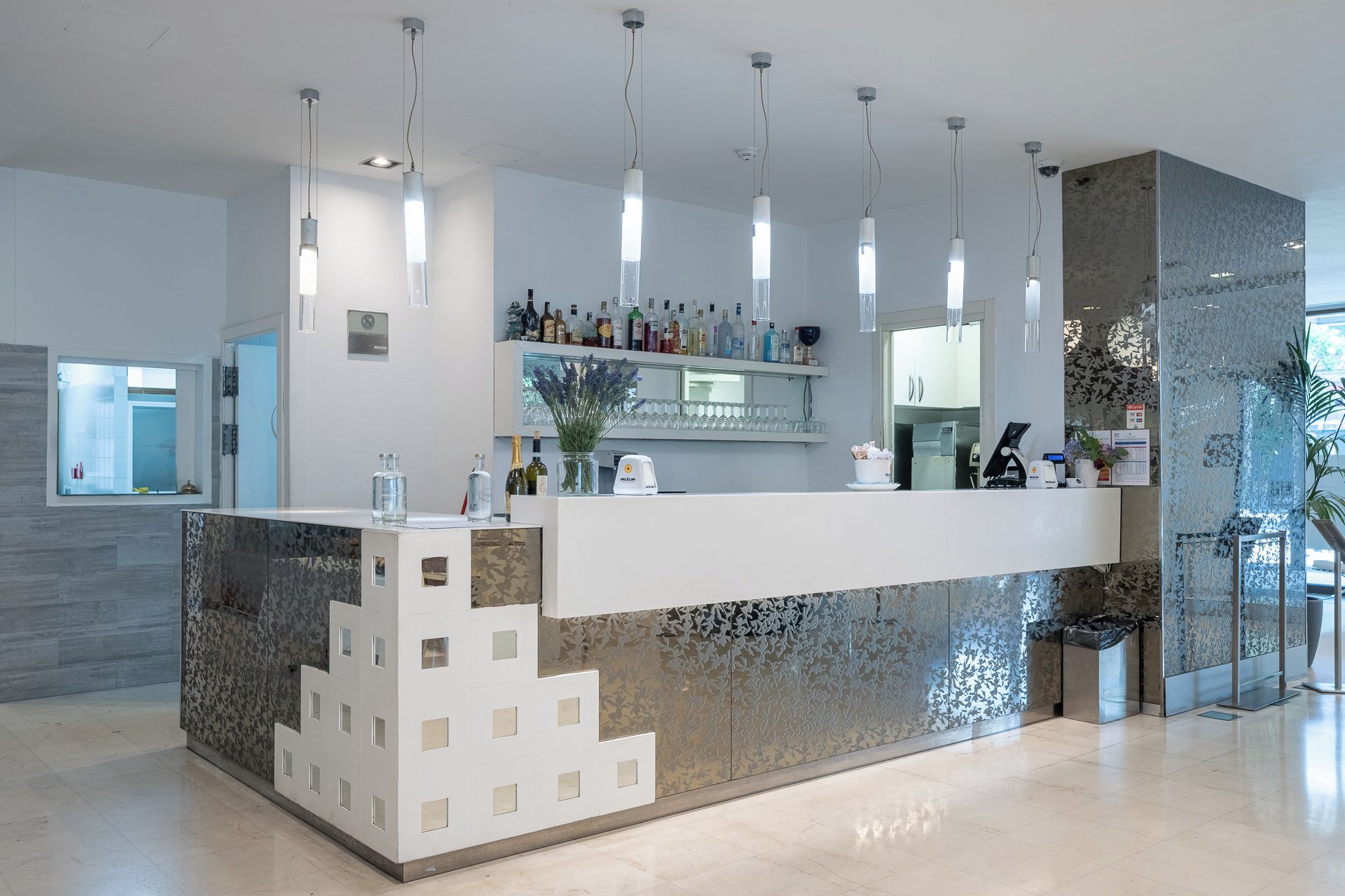 A modern reception area with a counter, overhead lighting, and a decorative wall.