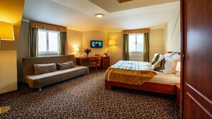 A hotel room with a bed, a sofa, a desk, and a television. - Hotel U Divadla (Prague)