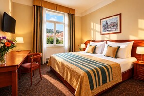 A hotel room with a bed, a desk, a chair, a television, and a window with a view of buildings. - Hotel U Divadla (Prague)