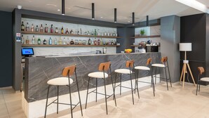 A modern bar area with a marble counter, multiple liquor bottles, and bar stools. - Hotel Ivka (Dubrovnik)