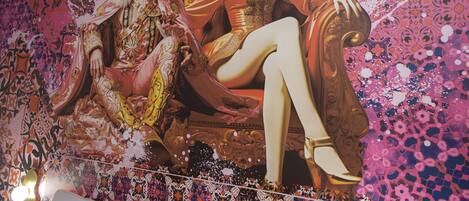 Un mural con una figura sentada en un trono, otra figura a su lado y un fondo con un diseño.
