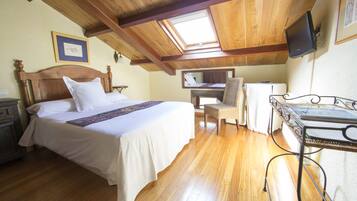 A bedroom with a wooden ceiling, a bed with white bedding, a chair, a desk, and a television.