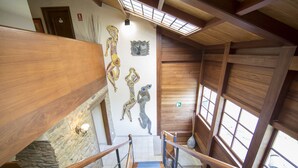 A wooden staircase with a stone wall and a mural. - Pazo da Trave (Viveiro)